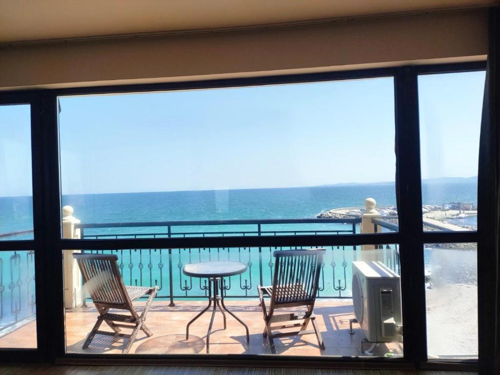 a balcony with a table and chairs and the ocean at Студиа При Американеца in Pomorie