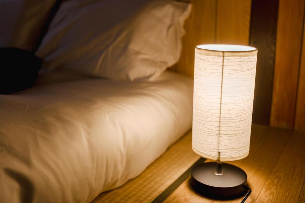 a lamp sitting on a table next to a bed at Imafuku Happiness Villa in Osaka