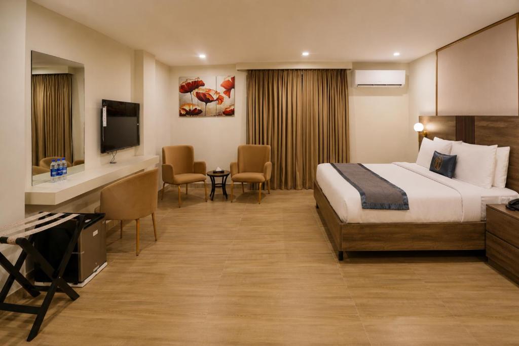 a hotel room with a bed and a television at RT Serene Hotel - Hyderabad in Hyderabad