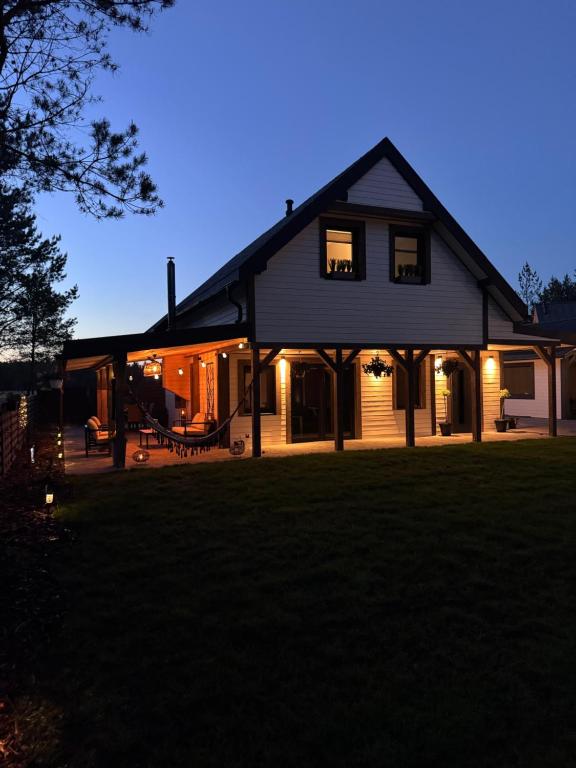 a large house with lights on in a yard at Wooden House Kaszuby in Borsk