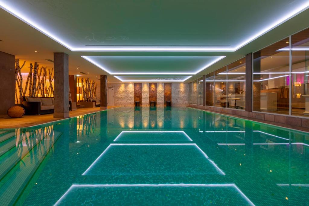 an indoor swimming pool with green water in a building at Sackmann Design Genuss & SPA Resort in Baiersbronn
