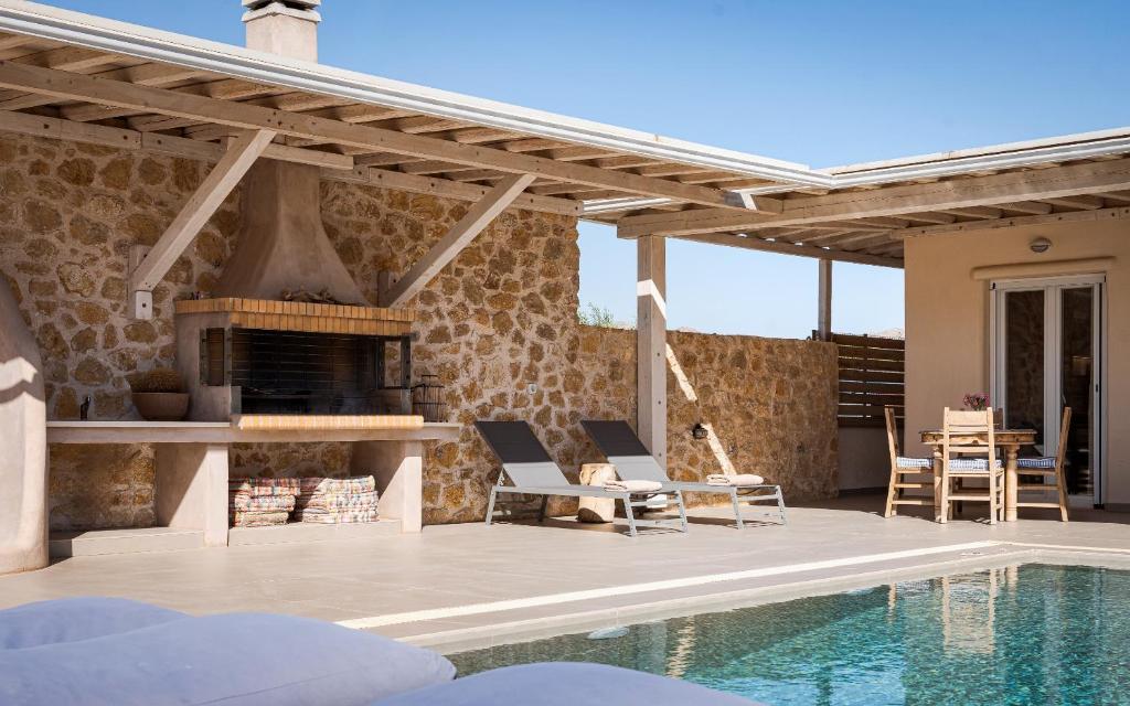 a patio with a fireplace and a swimming pool at Olive Tree House in Anavyssos