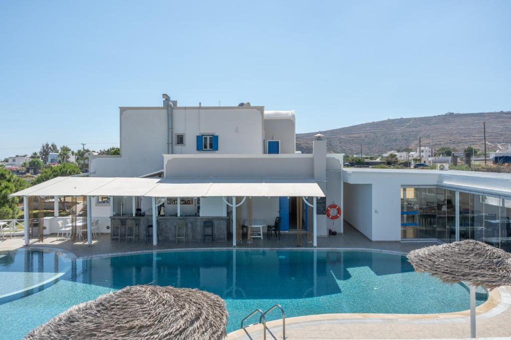 a swimming pool with two chairs and a building at Bella Santorini Hotel in Perivolos