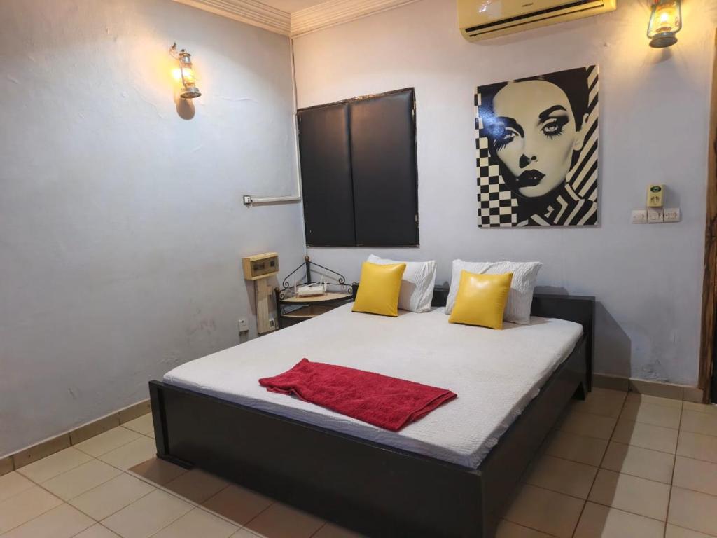 a bedroom with a bed with yellow and red pillows at La CASA - Guesthouse in Ouagadougou