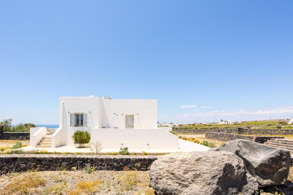 a white house with rocks in front of it at Assyr A - Santorini Cozy Cycladic Retreat in Akrotiri