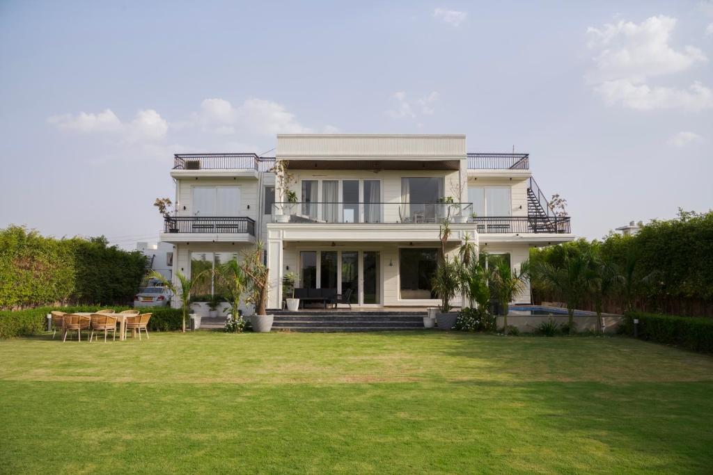a large house with a lawn in front of it at Saffronstays Olive Farms in Mandkaula