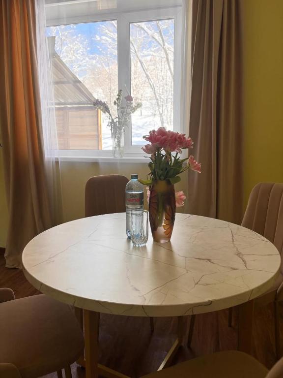 a table with a vase of flowers and a window at Дом твоей силы in Talghar
