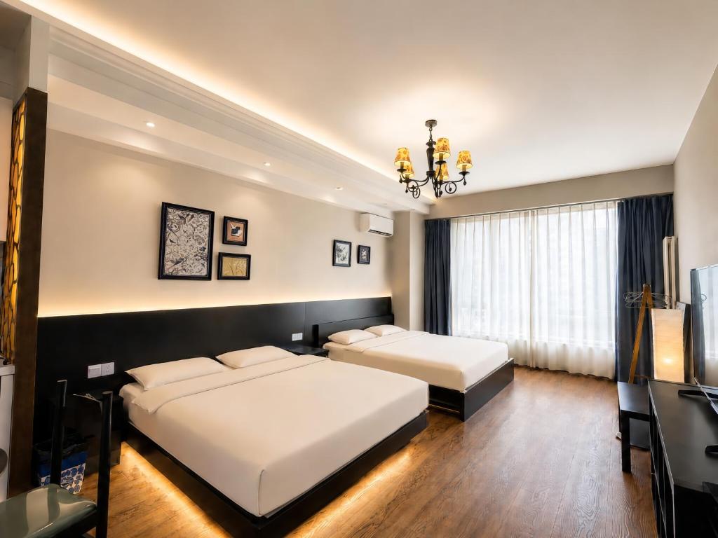 a bedroom with two beds and a chandelier at Anju Apartment in Beijing