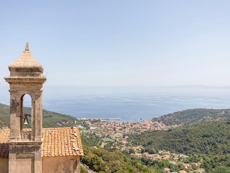 a building with a tower with a view of a city at Domina House by ElbaSummer in Marciana