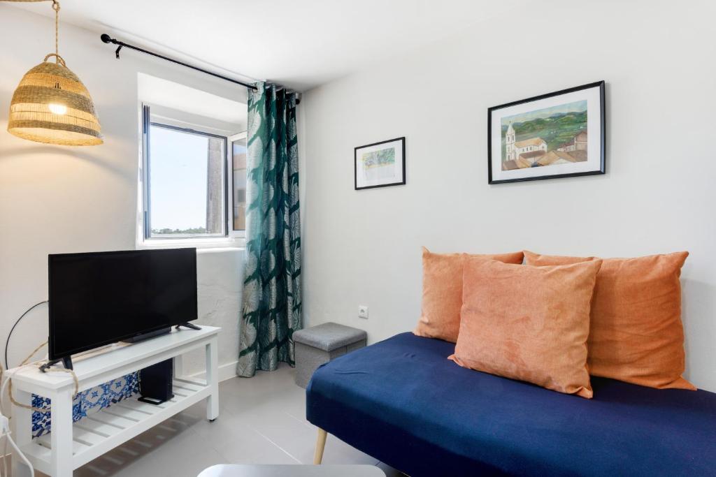 a bedroom with a blue bed and a flat screen tv at Casinha Peral Country Cottage in Peral