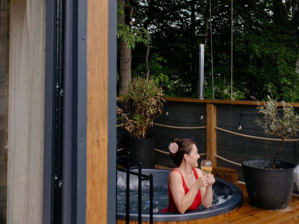 a woman sitting in a hot tub with a glass of wine at Okno na Beskidy -domek NIEBO z balią , sauną i niesamowitym widokiem na góry in Maków Podhalański