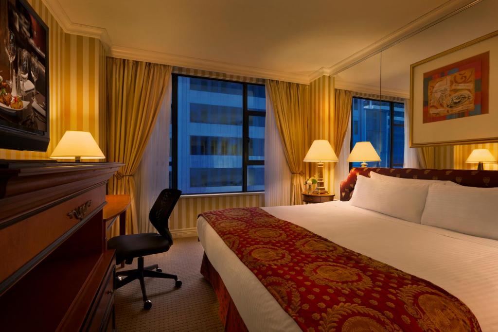 a hotel room with a bed and a desk and a window at Hotel Le Soleil by Executive Hotels in Vancouver