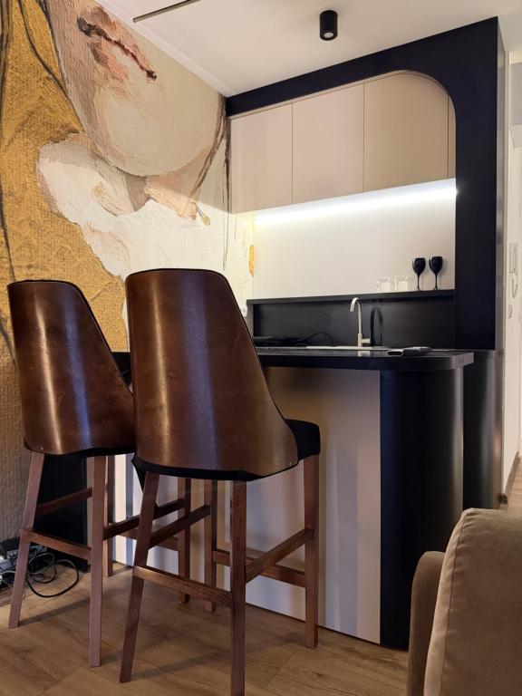 a kitchen with two black chairs and a counter at T&M Apartman Premium 2 in Paraćin