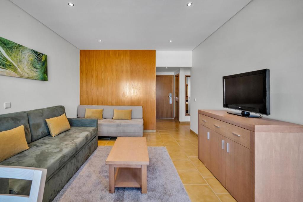 a living room with a couch and a flat screen tv at Albufeira Sol Hotel & Spa in Albufeira