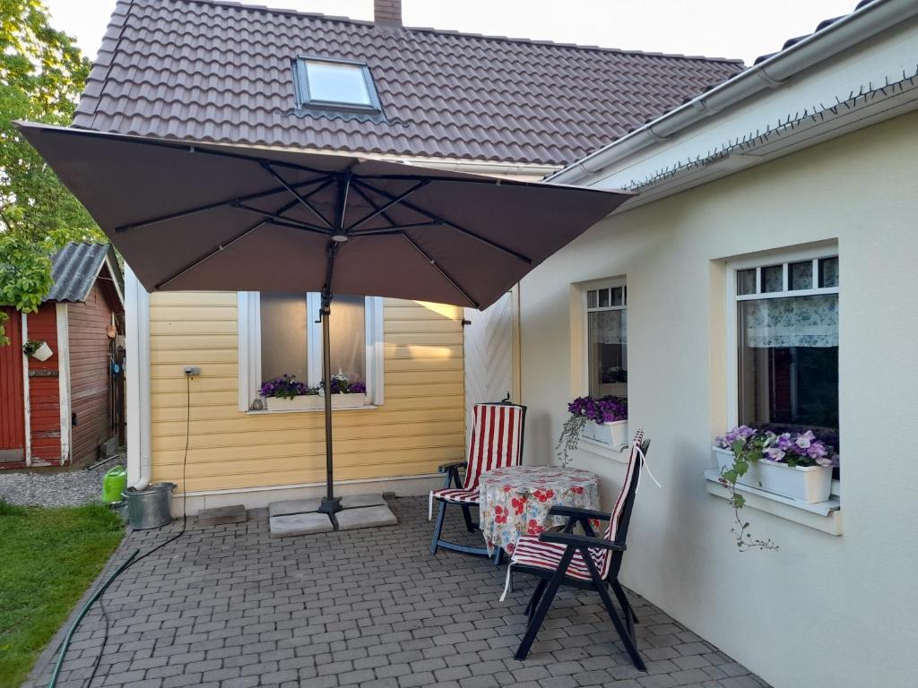 a table and chairs under an umbrella on a patio at Männi hoovimaja in Pärnu