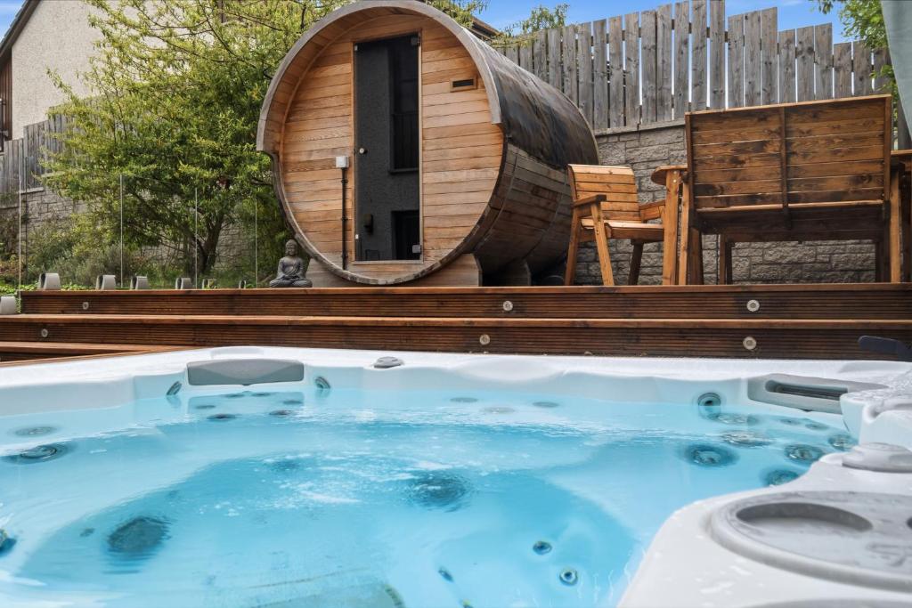 a hot tub in a backyard with a wooden tub at Glenisla, Aviemore, fantastic location with sauna and hot tub in Aviemore