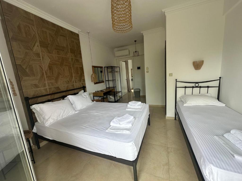 two beds in a room with white sheets at Apartments Villa Effie in Paralia Katerinis