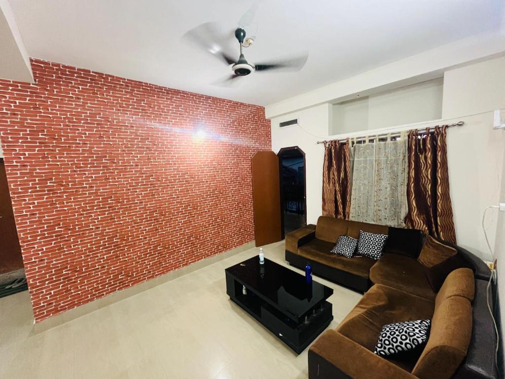 a living room with a brick wall and a couch at Phalchaa Stay in Jaigaon