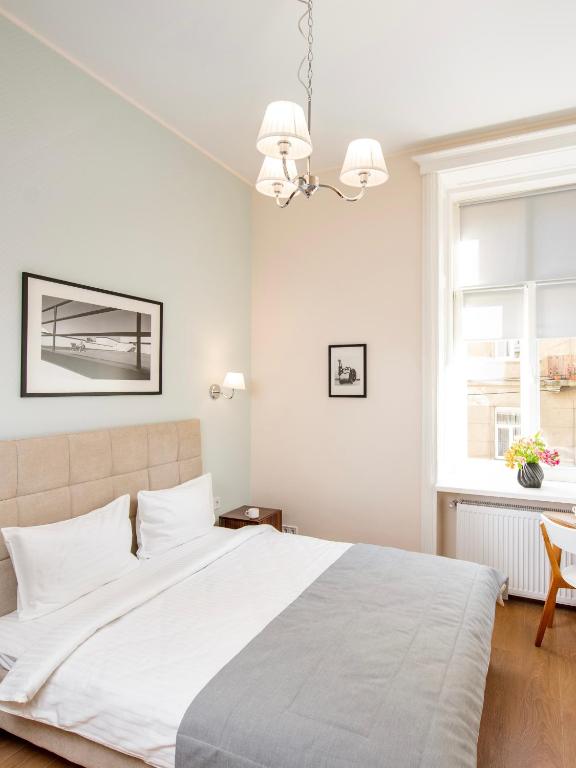 a bedroom with a large white bed and a window at Art Deco Central Rooms in Lviv