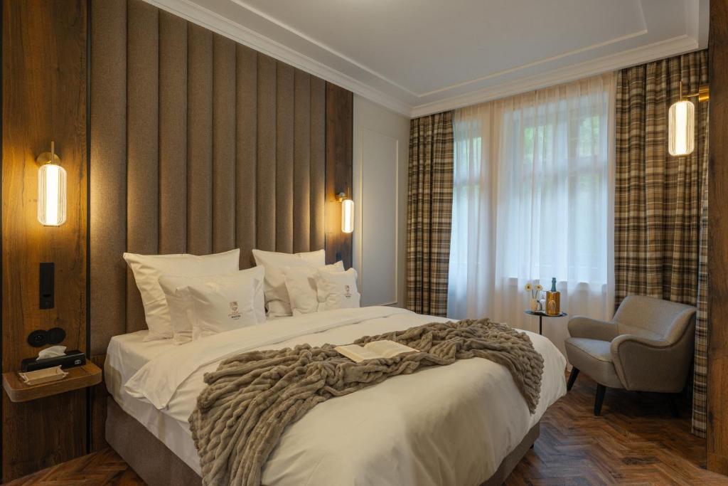 a bedroom with a large bed and a chair at Wanda Luxury Boutique Hotel - tylko dla dorosłych in Szczawnica