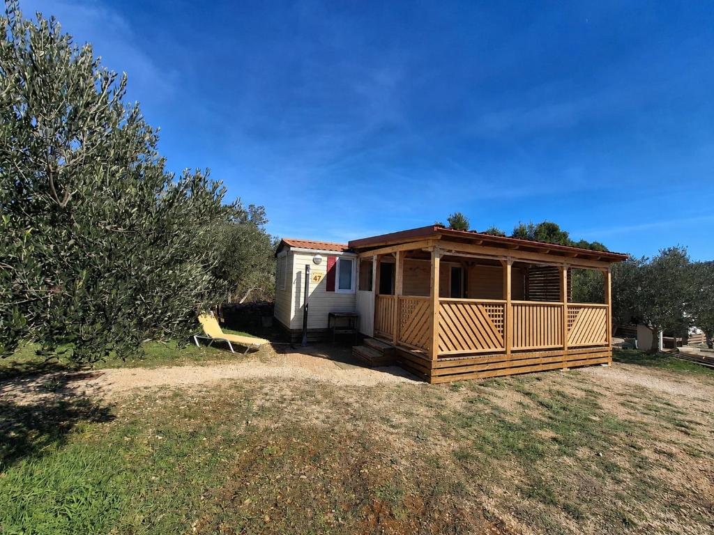 a house with a porch on a grass field at Mobile Home MEDITERRA in Pirovac