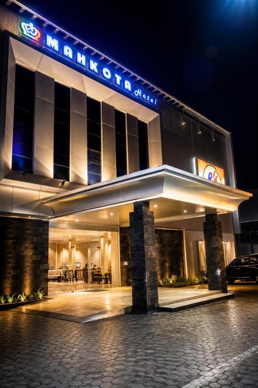 a hotel building with a sign on it at night at Mahkota Hotel in Genteng-kulon