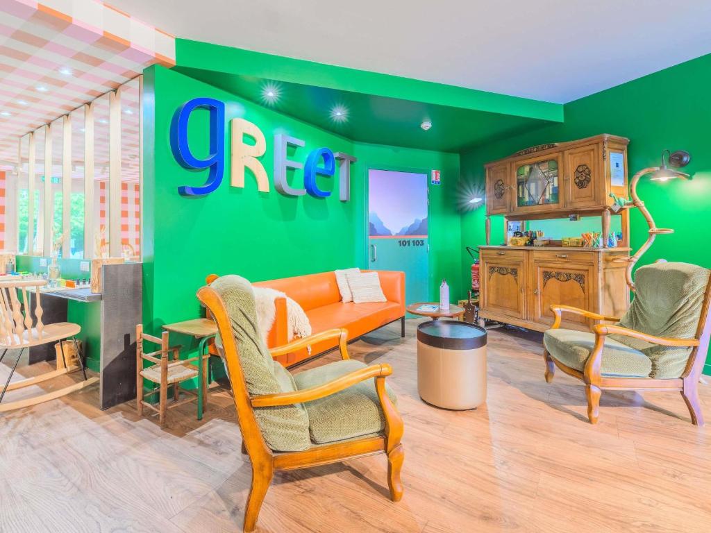 a living room with a green wall with a couch and chairs at greet hôtel Annecy Cran-Gevrier by Accor in Annecy