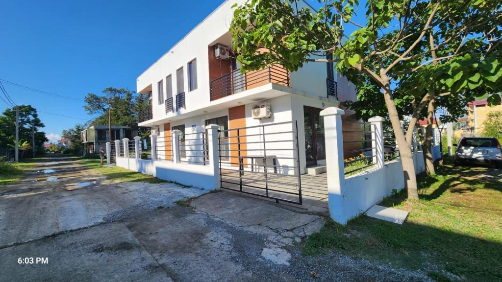 a white building with a fence next to a street at Rio cottage apartment in Ureki