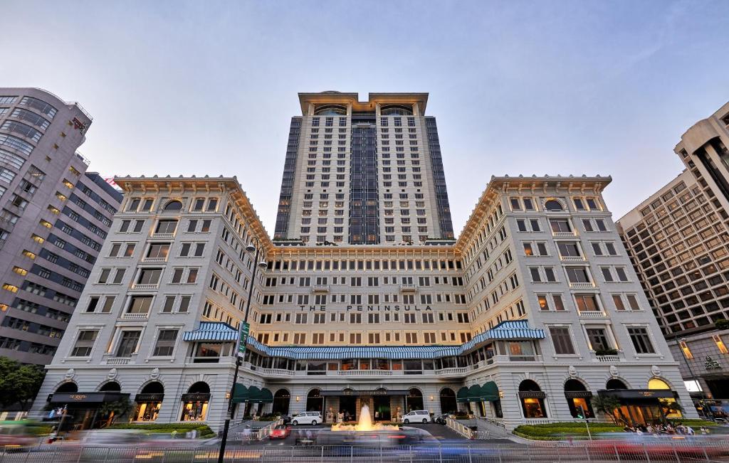 a large building with two tall buildings in a city at The Peninsula Hong Kong in Hong Kong