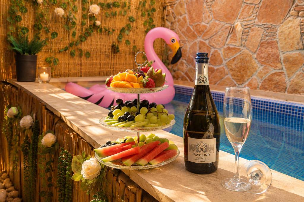a bottle of wine and plates of fruit next to a pool at Spa Mari TLV in Tel Aviv