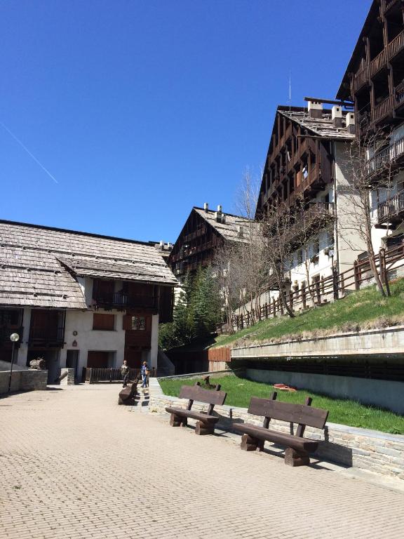 Eine Reihe von Parkbänken neben einem Fluss mit Gebäuden in der Unterkunft Sestriere-Sises Lodges, Appartamenti Moderni, vicino alle piste in Sestriere