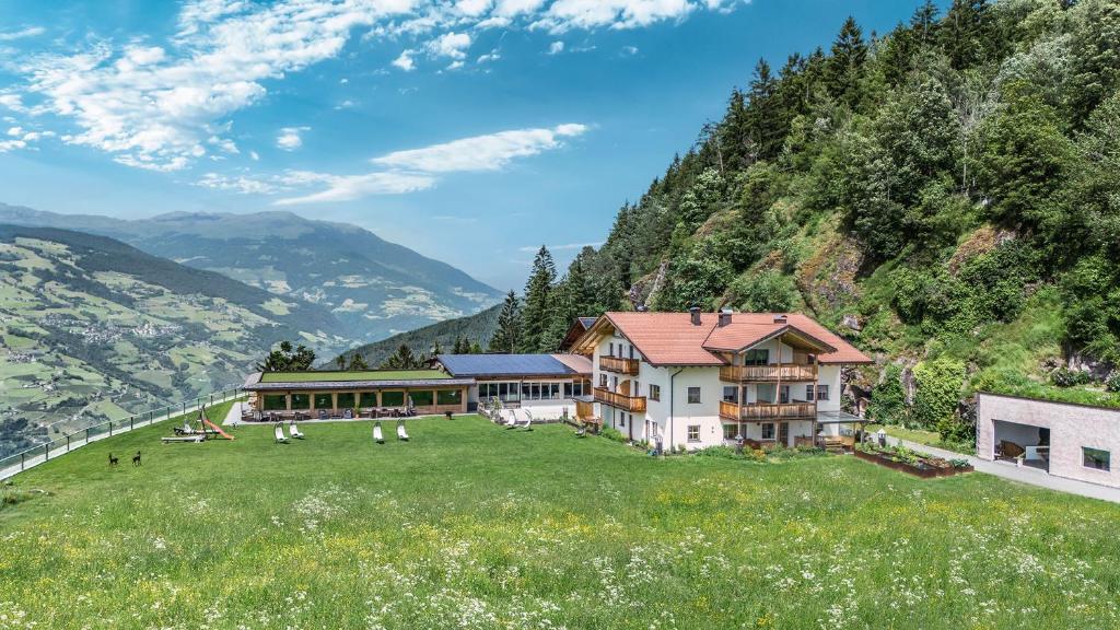 a house on a hill with a green field and mountains at Moarlhof - Farm Nature Resort in Castelrotto