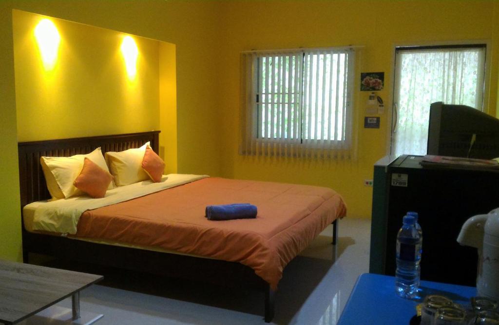 a bedroom with a large bed with yellow walls at Baan Benjathip in Amphawa