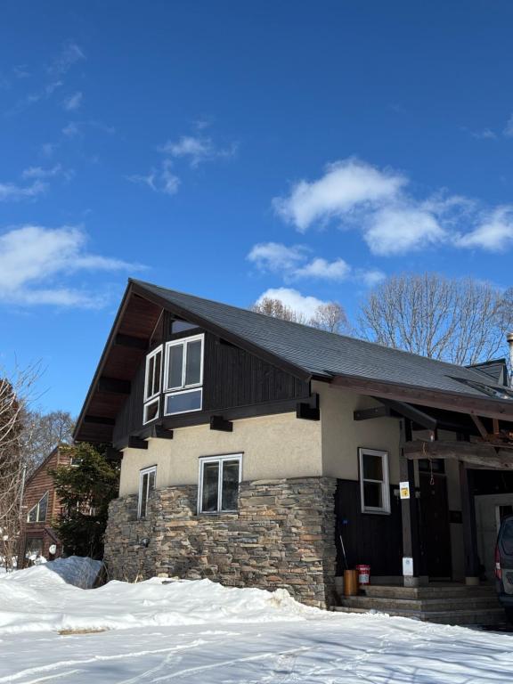 a house with a black roof in the snow at CALL92Chalet in Hakuba