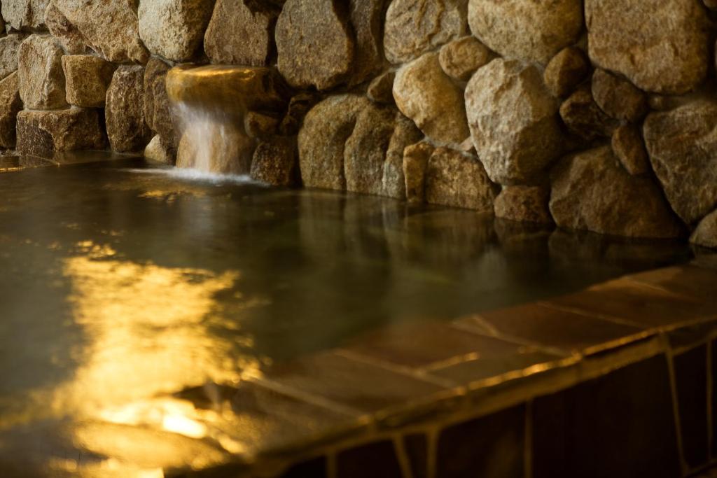 a water feature in a stone wall with a waterfall at New Grande Mimatsu in Takamatsu