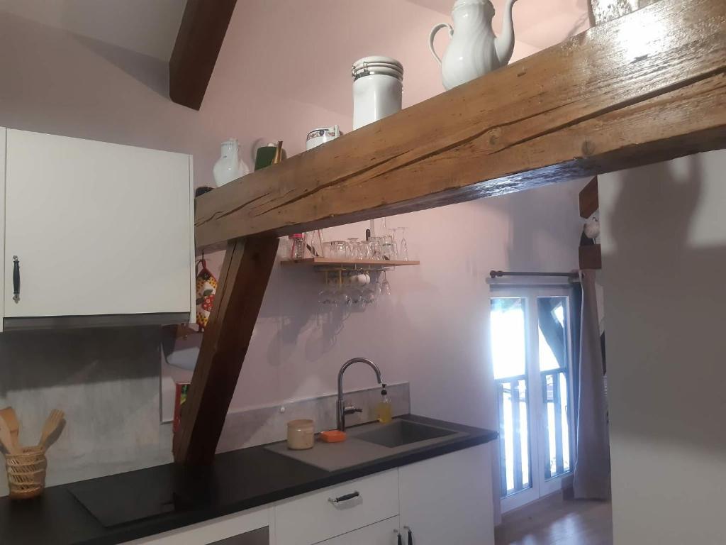 a kitchen with a sink and a wooden shelf above the sink at Gîte de l'Ancienne Forge in Epfig