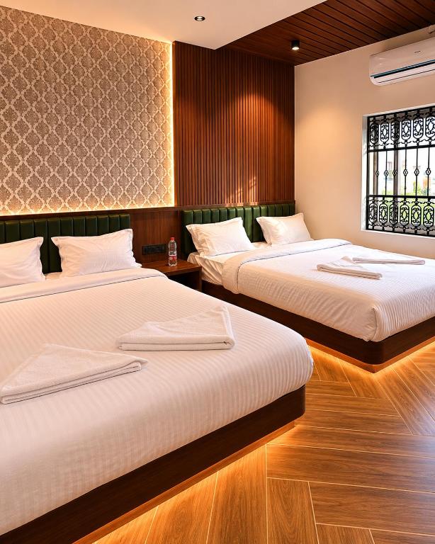 a bedroom with two beds and a window at Hotel J VIN PALACE in Mysore