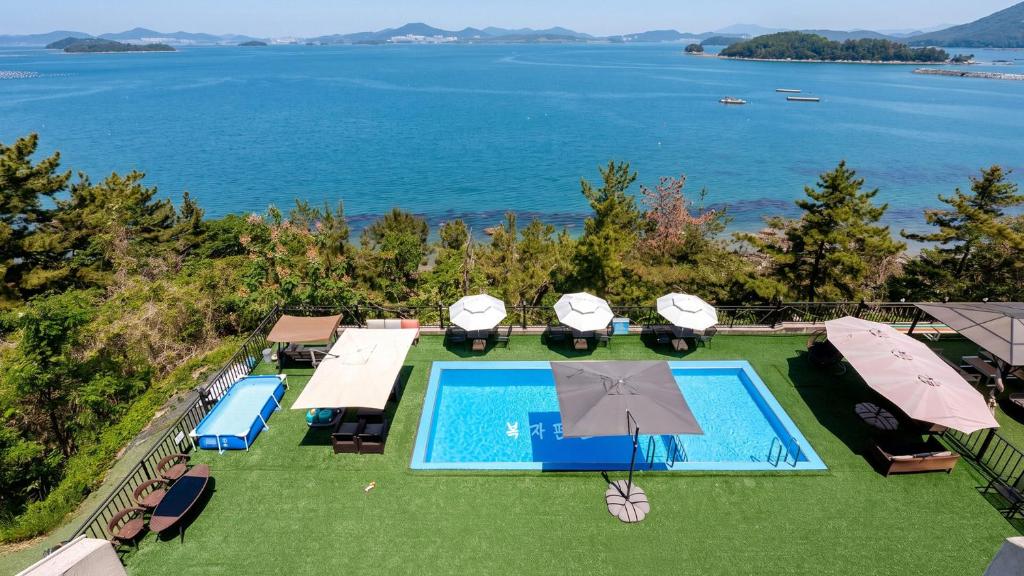 an aerial view of a swimming pool with umbrellas and the ocean at Yeosu Bokja Spa Pension in Yeosu