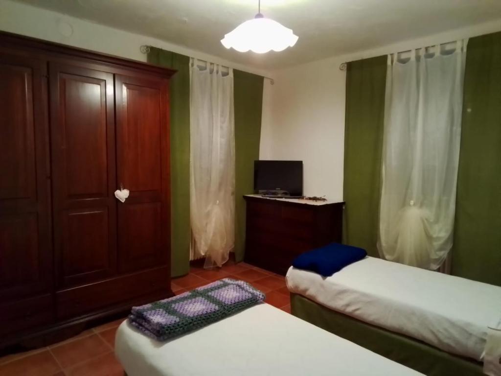 a room with two beds and a cabinet and a television at L'ora d'aria in Bardi