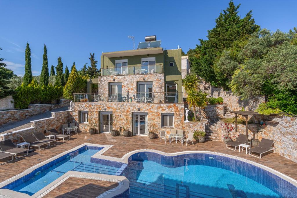 a villa with a swimming pool in front of a house at Kalokairi Boutique Residence in Skopelos Town