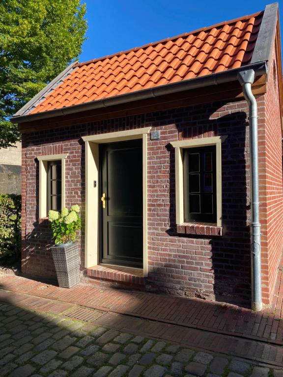 a small brick house with a black door and windows at Lüttje Huus Emden- Tiny House zentral am Hafen & Otto Huus in Emden