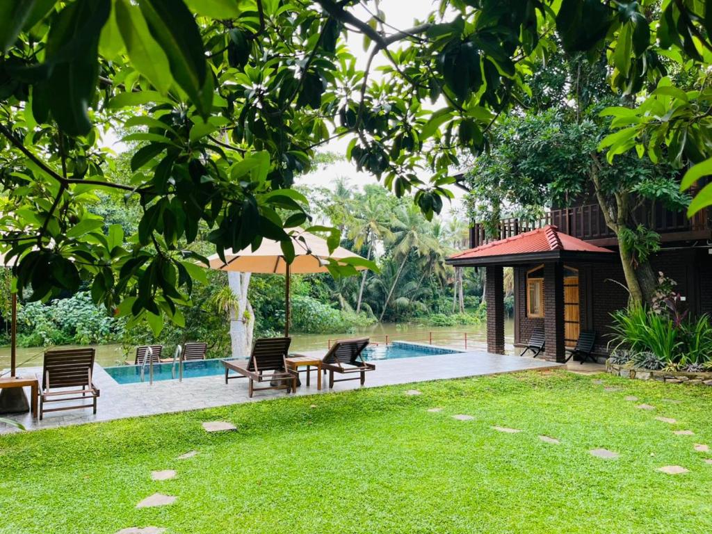 a backyard with a pool and chairs and a house at Yala River Face Inn in Tissamaharama