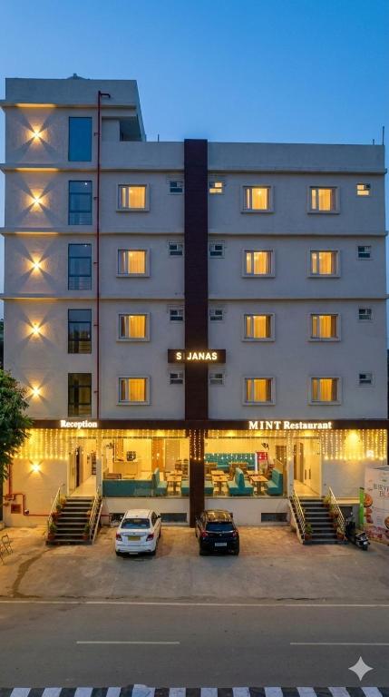 ein Gebäude mit zwei auf einem Parkplatz geparkten Autos in der Unterkunft Hotel JANAS in Tirupati