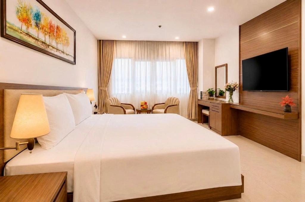 a hotel room with a large white bed and a desk at T78 Luxury Hotel in Ho Chi Minh City