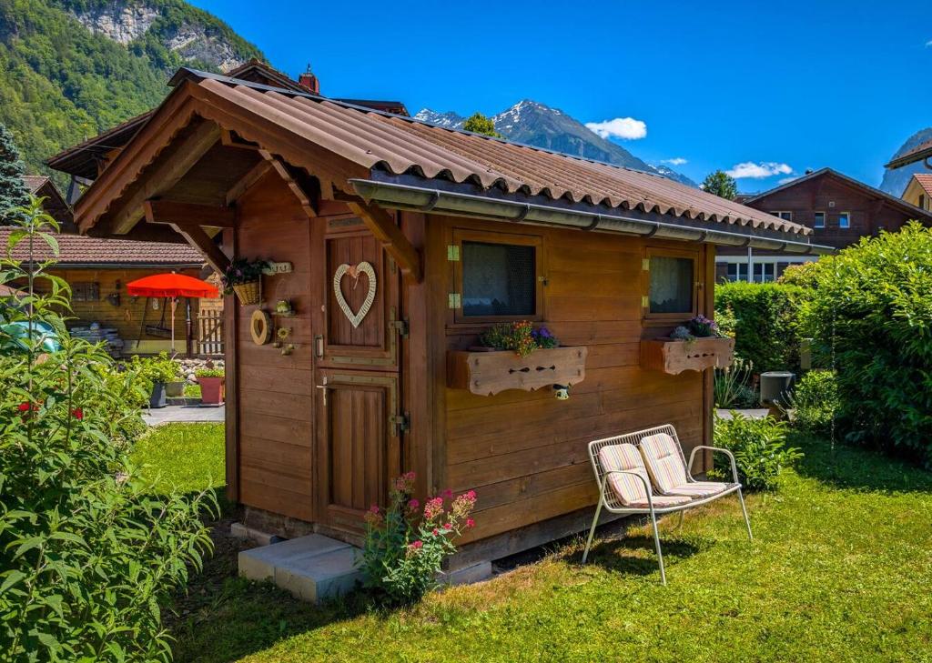 a small wooden house with a chair in the yard at Gemütliches Gartenhüttli mit Alpenblick in Meiringen