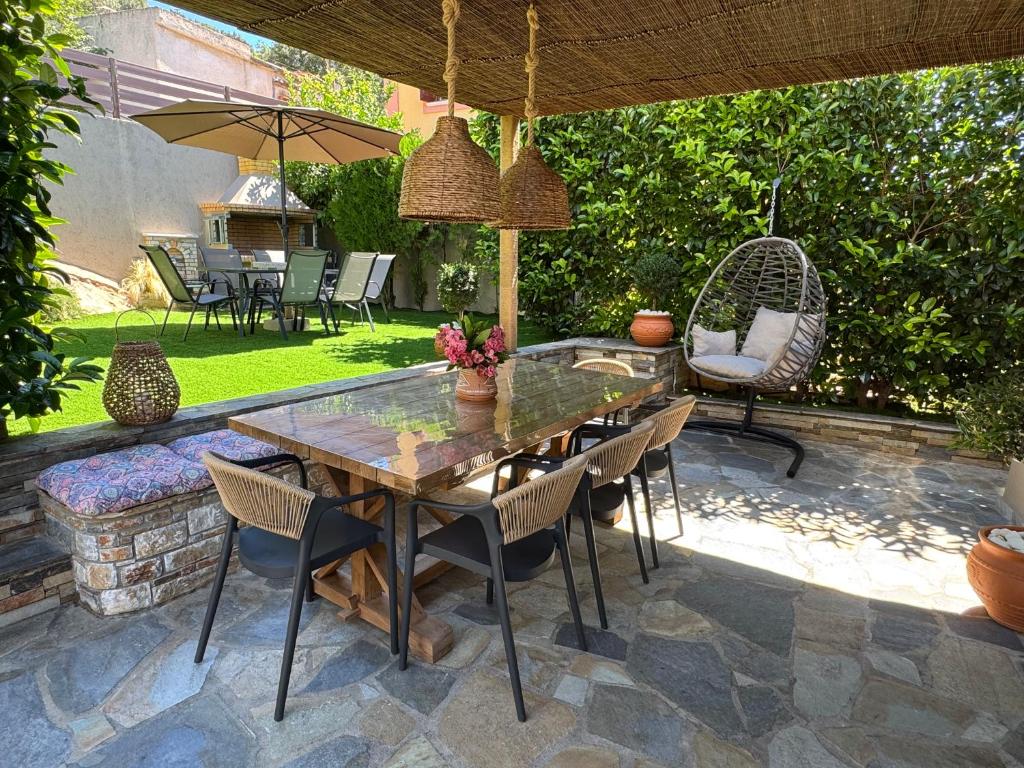 a patio with a table and chairs and an umbrella at Pelion PNOES Luxury Seaview Villa with priv Garden in Káto Lekhónia