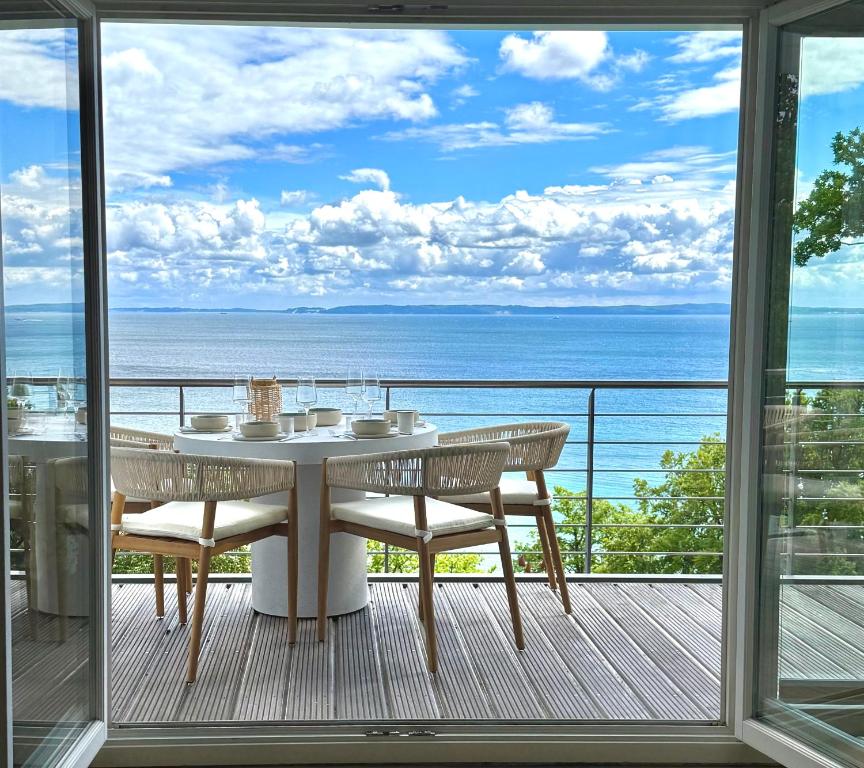 a table and chairs on a balcony with a view of the ocean at Sassnitz - Modernisiert 2026 - Outdoor Teich, Spa-Sauna, Fitness, Kamin - FeWo Fontane in Sassnitz