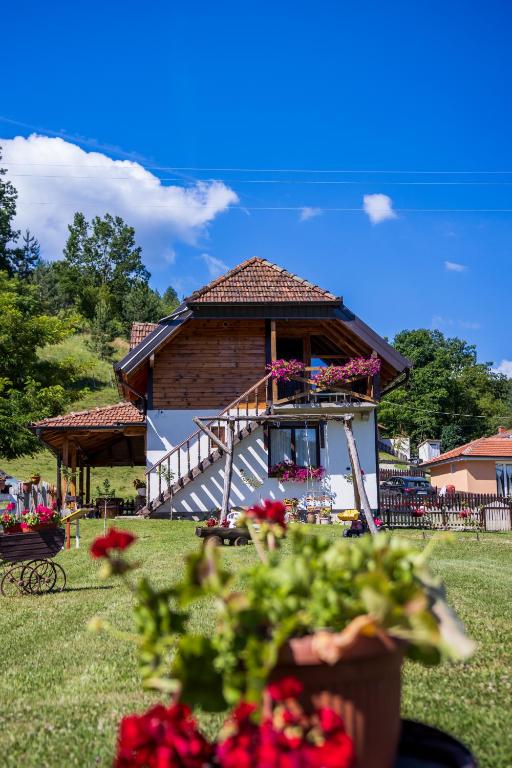 a house with a porch and flowers in a yard at Dolina Vekova in Banja