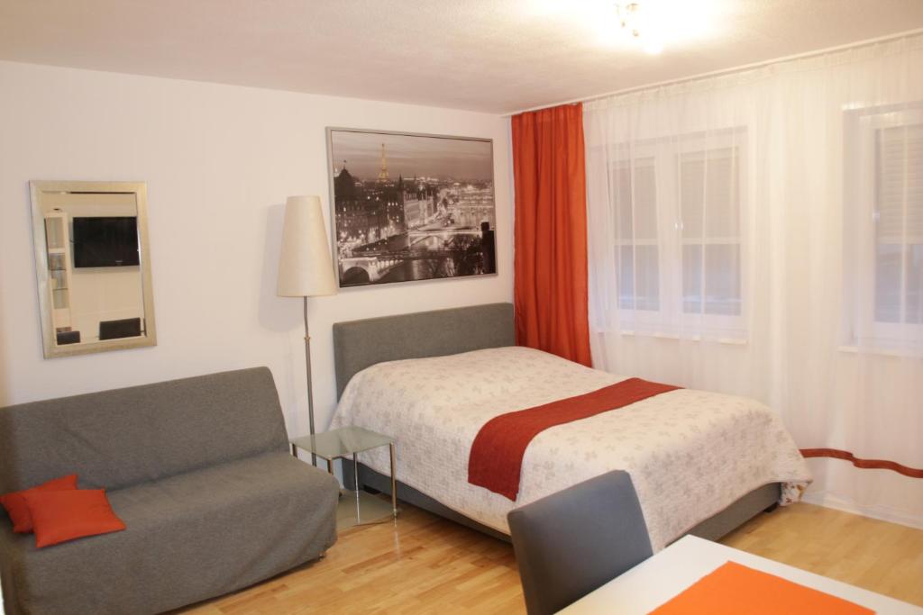 ein kleines Schlafzimmer mit einem Bett und einem Sofa in der Unterkunft Apartment Walldorf in Walldorf