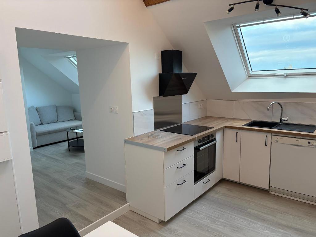 a kitchen with white cabinets and a sink and a window at Sur les toits de Beaugency in Beaugency
